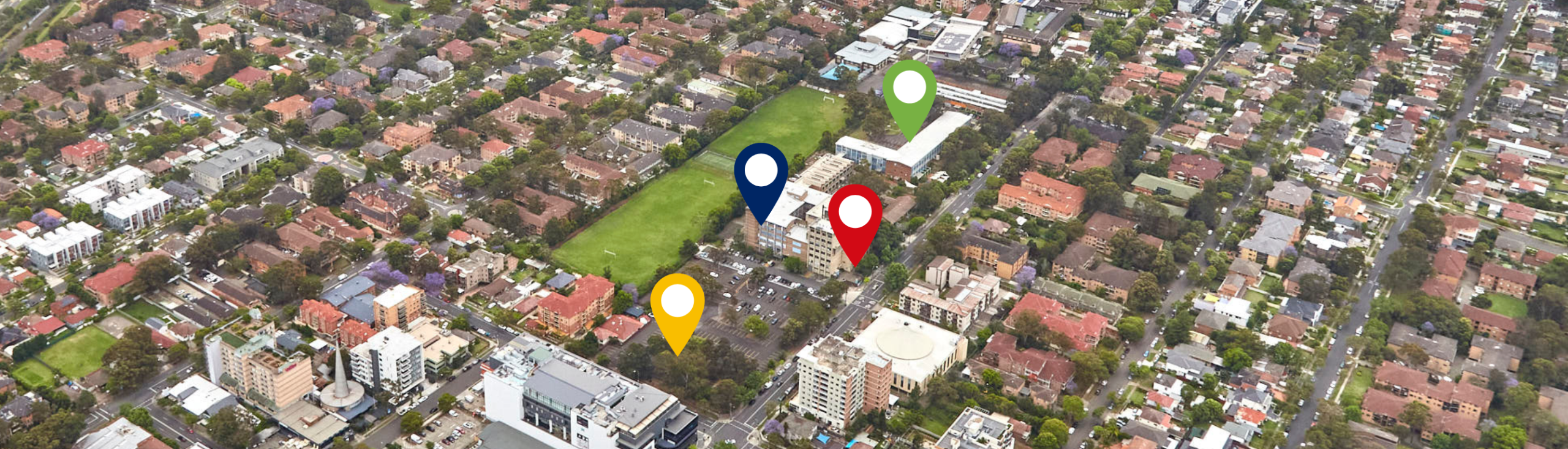 Aerial view of city buildings and green playing fields with colourful map icons