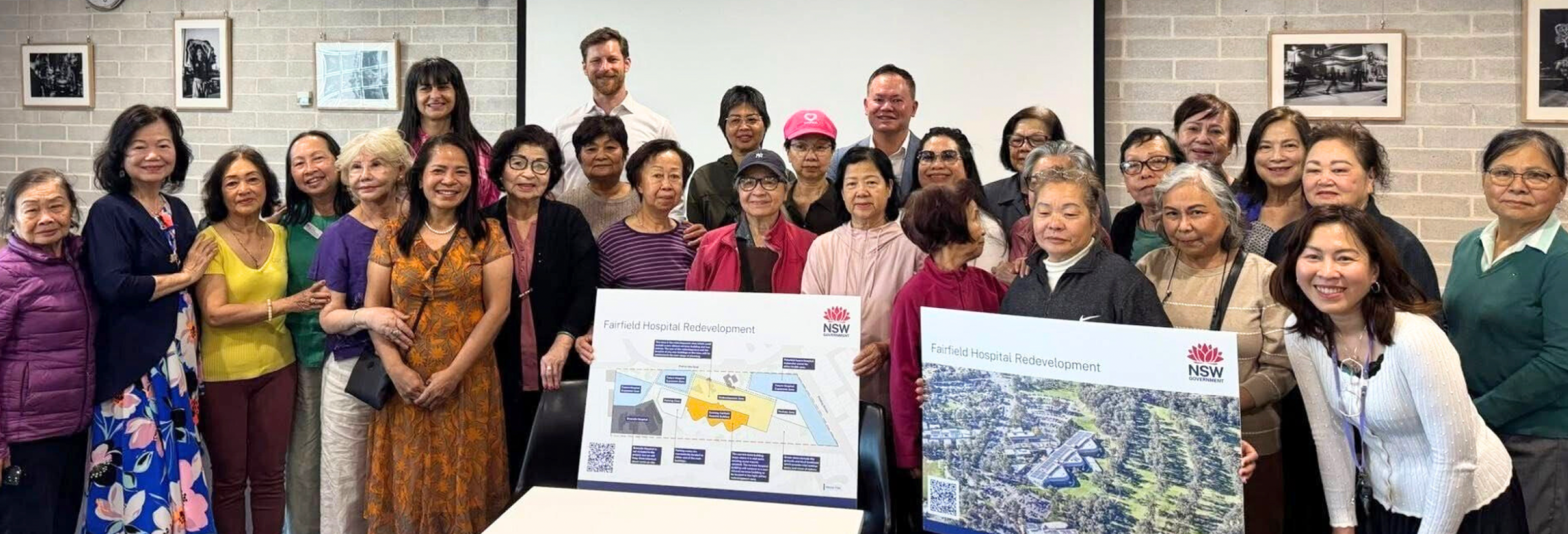 A group of people holding boards showing plans for the new hospital buiding