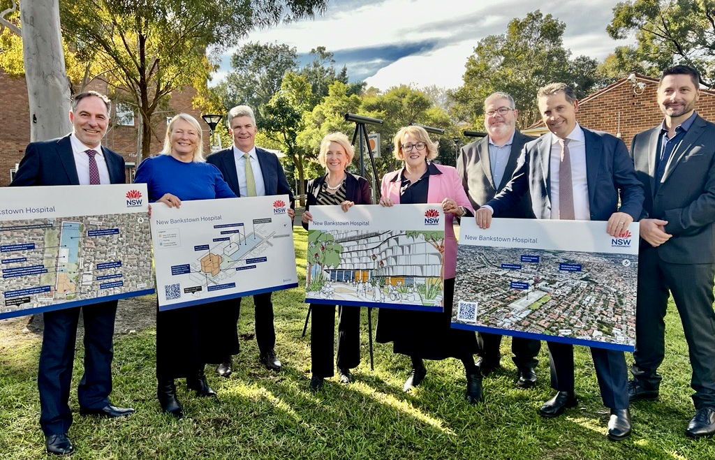 A group of people in business clothes holding plans for the new hospital
