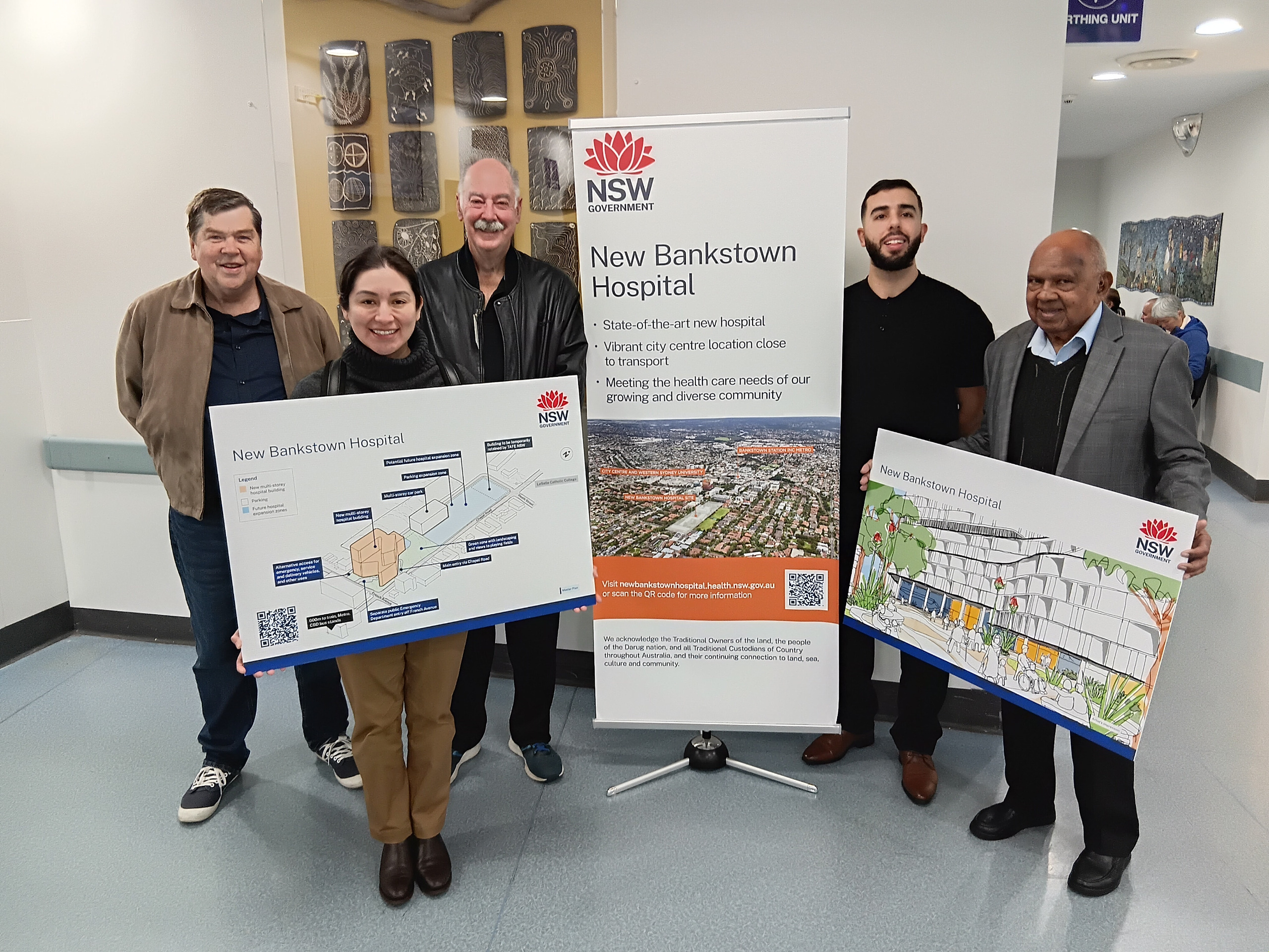 A group of people holding boards showing plans for the new hospital site